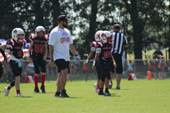 A Four Oaks coach on the field with Four Oaks players