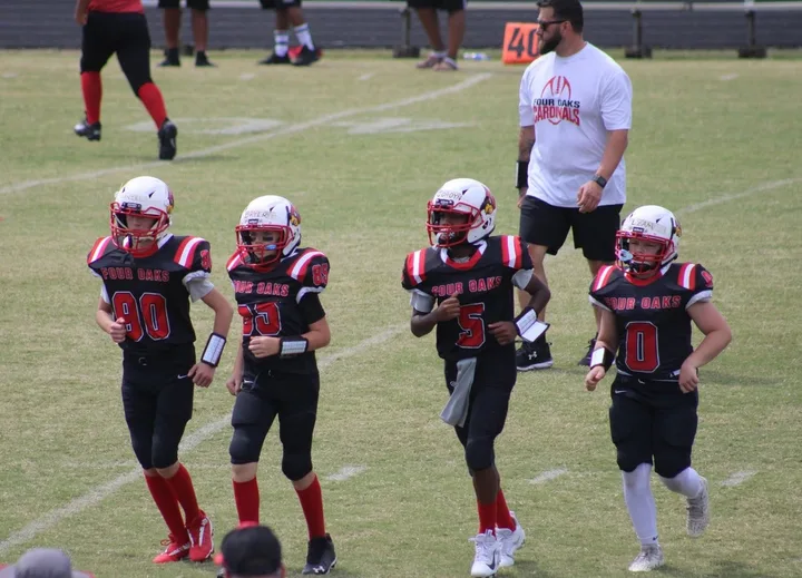 A Four Oaks coach walking onto the field with Four Oaks players